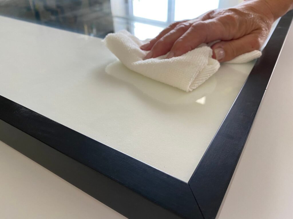 hand with a white towel wiping the surface of a glass frame for glass glazing